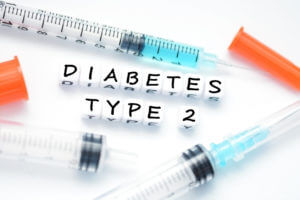 Type 2 diabetes text spelled with plastic letter beads placed next to an insulin syringe.