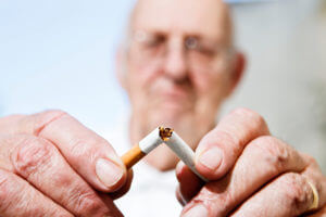 old man breaks cigarette to quit smoking due to his emphysema condition.